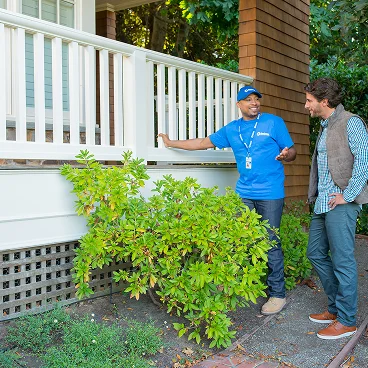 Home service professional reviewing project details with a homeowner near outdoor steps.